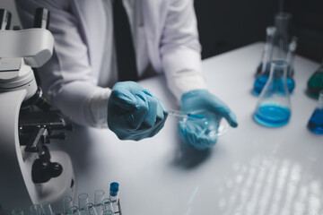 Lab assistant, a medical scientist, a chemistry researcher holds a glass tube through the blood sample, does a chemical experiment and examines a patient's blood sample. Medicine and research concept.
