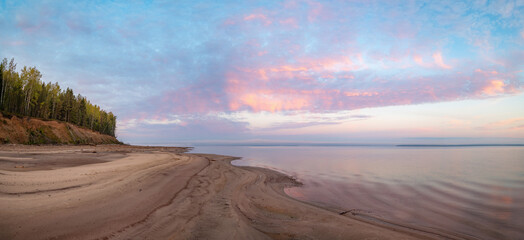 Pink dawn on the sandy bank of the Kama River, clouds in the distance fog, reflection in the water. - 650016124