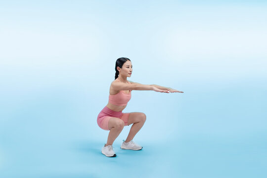 Vigorous energetic woman doing exercise. Young athletic asian woman strength and endurance training session as squat workout routine session. Full body studio shot on isolated background.