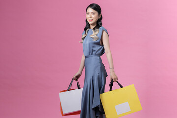 Asian woman holding shopping bags in full body isolated on pink background