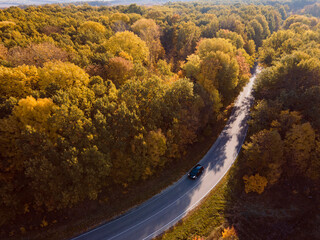 Fototapeta premium Aerial view of rural road with car in yellow and orange au