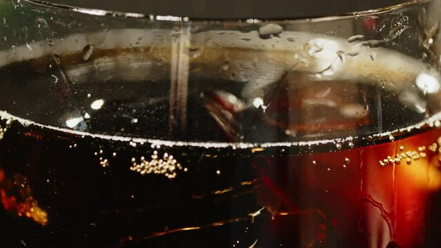 Close up of a glass of cola with ice cubes floating in the soda