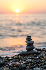 Stack of balanced stones on the beach during sunset, golden hour on the beach. Vertical photo