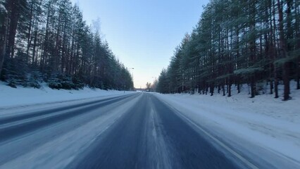 Pov footage of a car driving fast along a snowy country road on a crisp morning in Finland