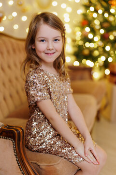 Smiling little girl sitting on sofa in christmas decorated room