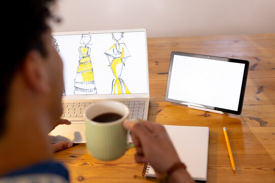 Focused biracial male fashion designer making video call in studio