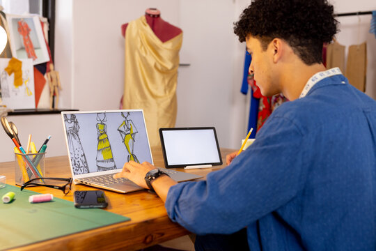 Focused biracial male fashion designer making video call in studio