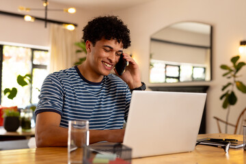 Happy biracial working at home and using laptop and smartphone