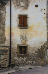 Fototapeta na wymiar Windows in an old stone house in the historic mountain village of Ovasta in Carnia, Udine Province, Friuli-Venezia Giulia, north east Italy