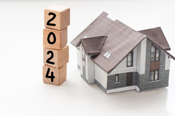 Wooden block with year 2024 text with money and toy house