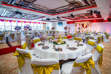 Indian Hindu temple wedding reception hall interiors, tables, chairs, glasses and plates