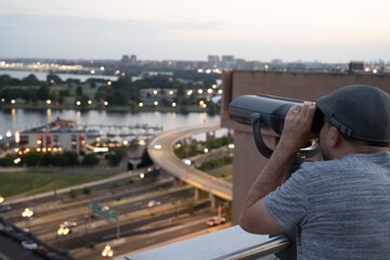 Un hombre mirando por unos binoculares a una ciudad desde un edificio