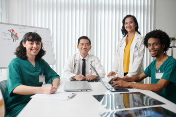 Happy medical team sitting at big table in office of clinic