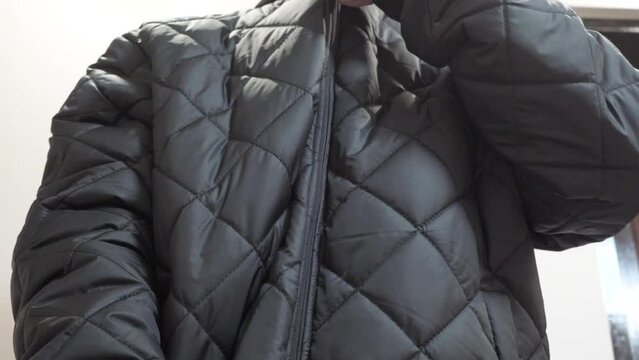 the boy put on a black jacket,a teenager in the room zips up his jacket