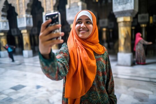 shot of a young muslim woman taking selfies at the haram jami mosque in indonesia