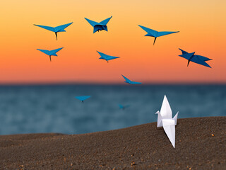 Pájaros de origami  volando sobre la playa al atardecer,  hora dorada,