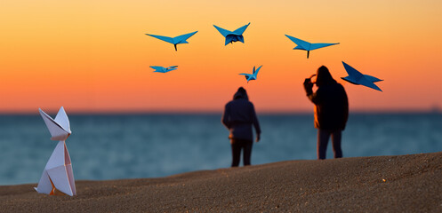 pajaros de origami volando sobre la playa al atardecer, Silueta  - obrazy, fototapety, plakaty