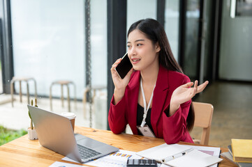 A professional and confident Asian businesswoman is talking with her business client on the phone.