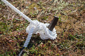 Fototapeta premium a strong rope tied to a metal post in the ground