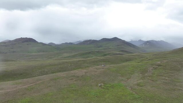 Accending Drone footage of green meadows and green land between the mountain of Pakistan, Desai Skardu while raining and drops on camera lens  