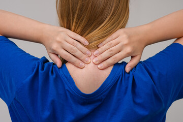Kobieta trzymająca dłonie na swoim karku, ból szyi z tyłu 