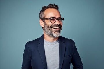 Portrait of a happy mature man in eyeglasses laughing against blue background - obrazy, fototapety, plakaty