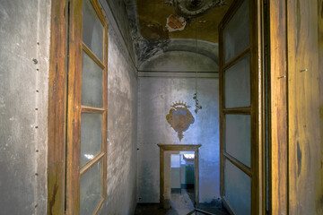 Windows open onto a frescoed corridor in an abandoned house