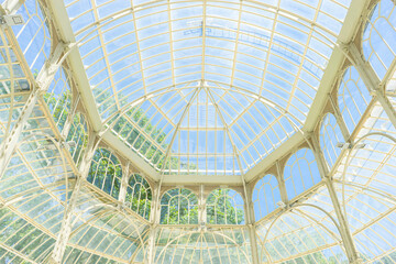 Sunlight through glass, nature's embrace. Marvel at Madrid's shimmering icon amidst tranquil greenery