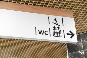 An information sign indicates directions to the toilet and stairs in a shopping center or other...