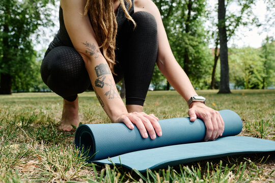 Close-up of young woman packing her exercise mat after training outdoors