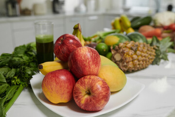 Plate with fresh ripe apples and bananas on kitchen counter