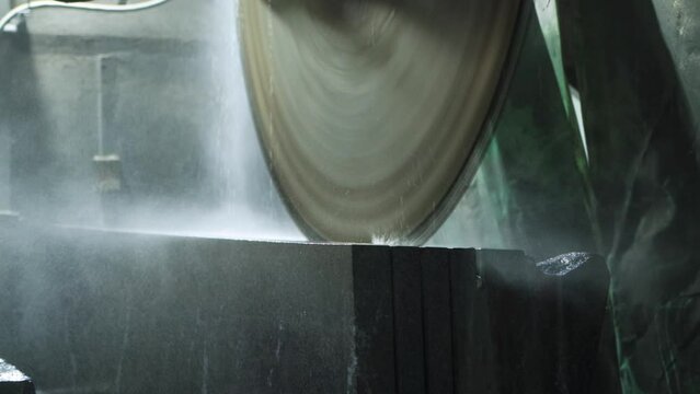 A large circular saw in a production facility cuts stoneware stoneware for thin slabs. Manufacture of slabs for monuments and decoration of facades of rooms from porcelain stoneware and granite, indus