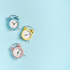 Collection of alarm clocks of different colors show different times. Start of the day, waking up, morning, different time zones.