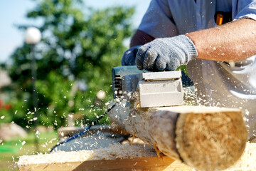 a carpenter works with an electric pipe on a sunny day
