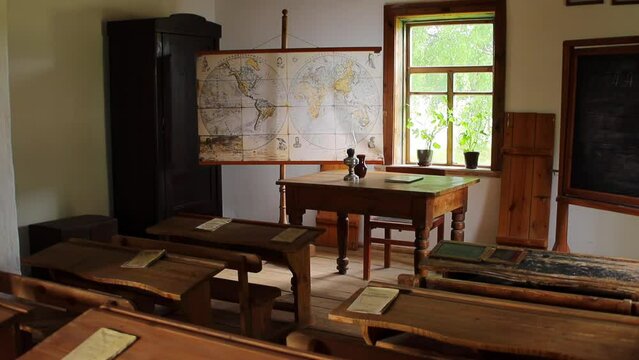 Old village classroom at school. Wooden tables and desks, rustic architecture. World map