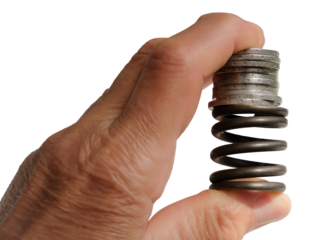 Coins on top of the metal spring.Old human hand.