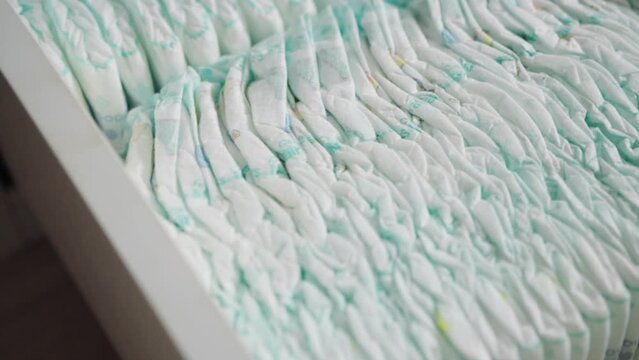 White dresser drawer full of baby diapers. Hygiene products against liquid leakage for children. Humidity indicator, cotton, close-up