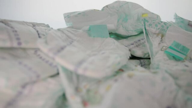 Scattered baby diapers on a table on a white background. The concept of hygiene and protection against leakage in children. Cotton comfort diapers. Copy space for text