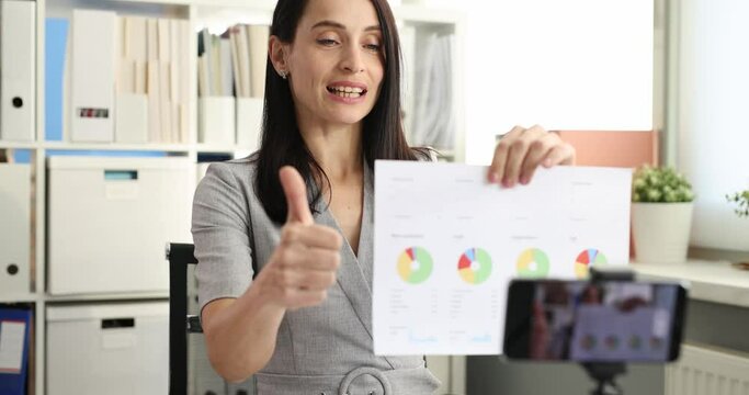 Employee analyzes client growth graph and records video on smartphone camera. Marketer broadcasts online and holds conference and compiles report