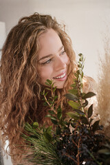 Naklejka premium Positive blond lady near green plants in studio