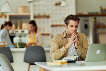 Busy man, working from home office while his wife and daughter cooking in the background.