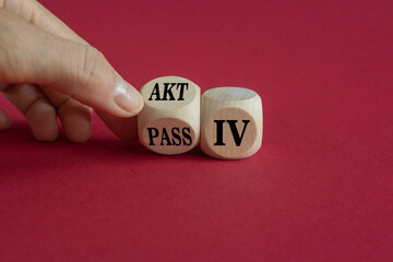 Hand turns dice and changes the German word passiv to aktiv. Beautiful red background. Copy space.