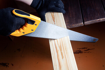 Close up the man use hand saw cutting wood board in the carpenter shop.