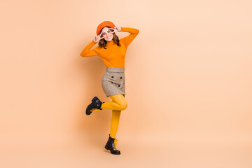 Full length photo of cheerful carefree lady wear trendy orange outfit arms showing v-sign empty...