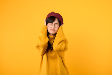 young 30s asian woman student expression desperate emotional stress feeling with closed ear with hand for silence to hear a noise sound against yellow background. unhappy desperate gesture concept.
