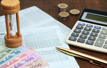 Book bank saving  with thai currency coins, banknotes, pen, calculator, wooden hourglass,bank...