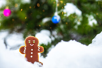 Christmas background. Festive gingerbread in a snowy forest, standing near a Christmas tree.
