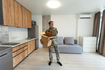 Patriotic military man in uniform keeps box in new apartments. Buying a property