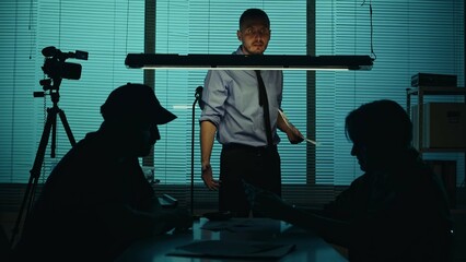 Silhouette, medium shot of an offender, perpetrator or prisoner sitting in the interrogation room...