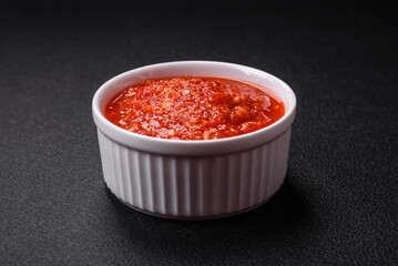 Delicious hot spicy red sauce with salt and spices in a ceramic bowl